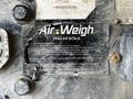 A close-up of a damaged Air-Weigh trailer scale label on a steel dump trailer displaying weight information and usage instructions for accurate weighing