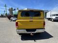 A yellow 2015 RAM 1500 pickup truck viewed from the rear with a black bed cover and chrome bumper
