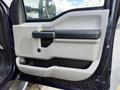 Door panel of a 2017 Ford F-550 featuring a light gray design with a black handle and storage area