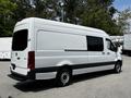 A white 2019 Mercedes-Benz Sprinter van with a long body and dark lower stripe parked at an angle