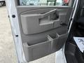 Close-up of the door panel of a 2019 Chevrolet Express featuring a textured gray surface and storage compartments for drinks and small items