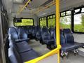 Interior view of a 2019 Chevrolet Express with rows of blue seats and yellow handrails for passengers