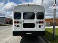 A 2022 Blue Bird BB Conventional school bus viewed from the rear featuring red and amber lights and an emergency door with a sign above it