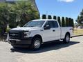 A white 2016 Ford F-150 pickup truck with a black grille and silver wheels is parked, showcasing its front and side profile
