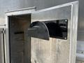 A black metallic flap door is partially open on the side of a silver 2008 Morgan Olson Workhorse vehicle revealing an empty compartment inside
