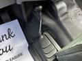 A gear shift lever inside a 2016 Ford F-550 vehicle showing a black rubber boot and a textured floor mat underneath