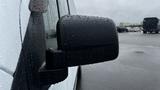 A close-up of a side mirror on a 2012 Ford Transit with droplets of water on its surface