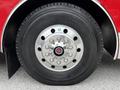 Close-up of a chrome wheel with multiple polished lug nuts and a large tire mounted on a red fire apparatus