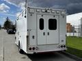 A white 2013 Chevrolet Express with double rear doors has emergency lights on top and is equipped for medical or emergency response use