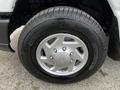 Close-up of a silver wheel from a 2011 Ford Econoline showcasing a five-spoke design and a black tire with marked tread pattern