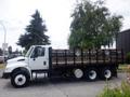 A 2015 International 4400 flatbed truck with a wooden stake body and dual rear wheels parked on a lot