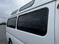 A 2002 Nissan Van with a white exterior and multiple tinted windows showing raindrops on the glass