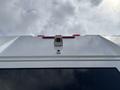 A white 2020 Chevrolet Express van with a camera mounted on the roof and red lights above the rear windows