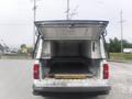 A 2015 Chevrolet Silverado 1500 with the truck bed open displaying a metal interior and a yellow loading ramp inside