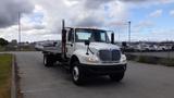 A white 2015 International DuraStar 4300 flatbed truck with a chrome grille and multiple reflectors on the cab