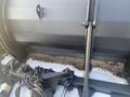 A large black plow attachment with a twelve-foot blade connected by metal brackets and chains
