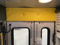 A 2014 Chevrolet Express with a yellow padded safety barrier above the rear doors and visible emergency release signs on the door panels