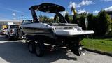 A 2023 Mercury Monterey boat with a black and white design, a sleek hull, and an open cockpit featuring seating and a bimini top mounted on a dual-axle trailer