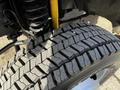 Close-up of a rugged tire from a 2011 Ford F-450 SD showcasing deep treads and a sturdy suspension spring next to it