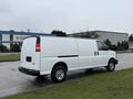 A white 2014 GMC Savana van parked on a surface with grass nearby, featuring a side door and windows on the driver's side