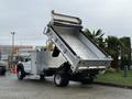 A 2012 Ford F-550 dump truck with its bed raised, revealing the shiny metal interior designed for hauling materials
