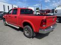 A red 2012 RAM 2500 truck with a crew cab parked at an angle showing the rear and side profile with chrome accents and large off-road tires