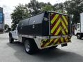 A 2016 Ford F-550 with a utility body featuring black compartments and red and yellow reflective markings on the back