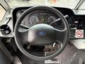 The steering wheel and dashboard of a 2012 Ford Econoline featuring gauges and controls with a Ford logo in the center