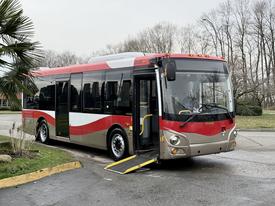 A red and gray 2016 Grande West Vicinity bus with an open door and a wheelchair ramp extended on the side