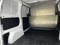 The interior of a 2020 Nissan NV200 van showing a spacious cargo area with a metal partition and black floor lining