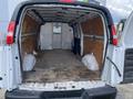 Interior view of a 2023 GMC Savana cargo van showing a spacious and empty cargo area with wooden flooring and back doors open