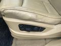 A close-up of the driver's seat adjustment controls of a 2009 BMW X5 featuring a beige leather seat with buttons for seat positioning