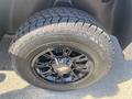 Close-up of a black alloy wheel with a rugged tire featuring thick treads designed for off-road use on a 2021 RAM 1500