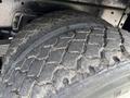 Close-up of a worn tire on a 1998 Freightliner FL80 showcasing deep tread patterns and weathered rubber surface