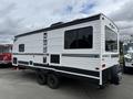 A 2022 Keystone Hideout RDWE 20RDWE travel trailer with a white exterior and large windows on the side featuring a black logo on the rear side and a spare tire mounted on the back