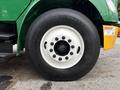 A close-up view of a 2015 Freightliner M2 106 tire featuring a black tread and white rim with several lug nuts securely fastened around the center hub