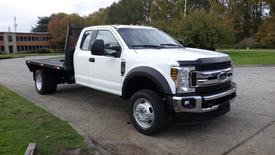 White 2019 Ford F-550 with a flatbed and dual rear wheels parked on a paved surface