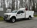 A 2019 Ford F-350 SD in white with a service body and equipment mounted on the bed