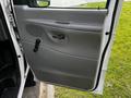 The interior side of a 2004 Ford Econoline van door showing a crank handle and speaker grille