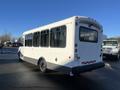 A white 2012 Chevrolet Express bus with large windows and a gray lower panel is parked, showing its rear and side features