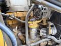 A close-up view of the engine and hydraulic components of a 2011 John Deere 310SJ 4x4 Wheel Loader with visible pipes and filters