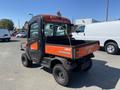 A 2018 Kubota ATV with an orange and black body and a covered cab built for maintenance use featuring a flatbed in the rear