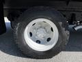 Close-up of a white wheel with a silver center hub mounted on a black tire designed for a 2007 GMC W3500