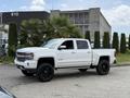 A white 2017 Chevrolet Silverado 1500 with a lifted suspension and black wheels parked on a street