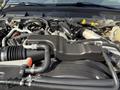 Close-up view of the engine components of a 2015 Ford F-550 showing various hoses and a black plastic cover over the engine compartment