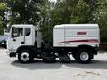 A 2012 Autocar Xpert street sweeper with a white and red Elgin Crosswind body and a front-mounted broom for cleaning roads and sidewalks