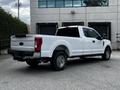A white 2017 Ford F-250 truck with a crew cab and a flatbed is parked prominently, showcasing its robust design and large wheels