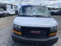 A 2023 GMC Savana van is shown from the front with a white body and black grille featuring the GMC logo in the center