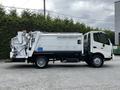 A 2014 Hino 195 truck with a white body and a waste collection apparatus on the side is parked prominently, showcasing its compact design and utility features
