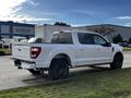 2021 Ford F-150 in white with a sporty design featuring a covered bed and black wheels parked on a street